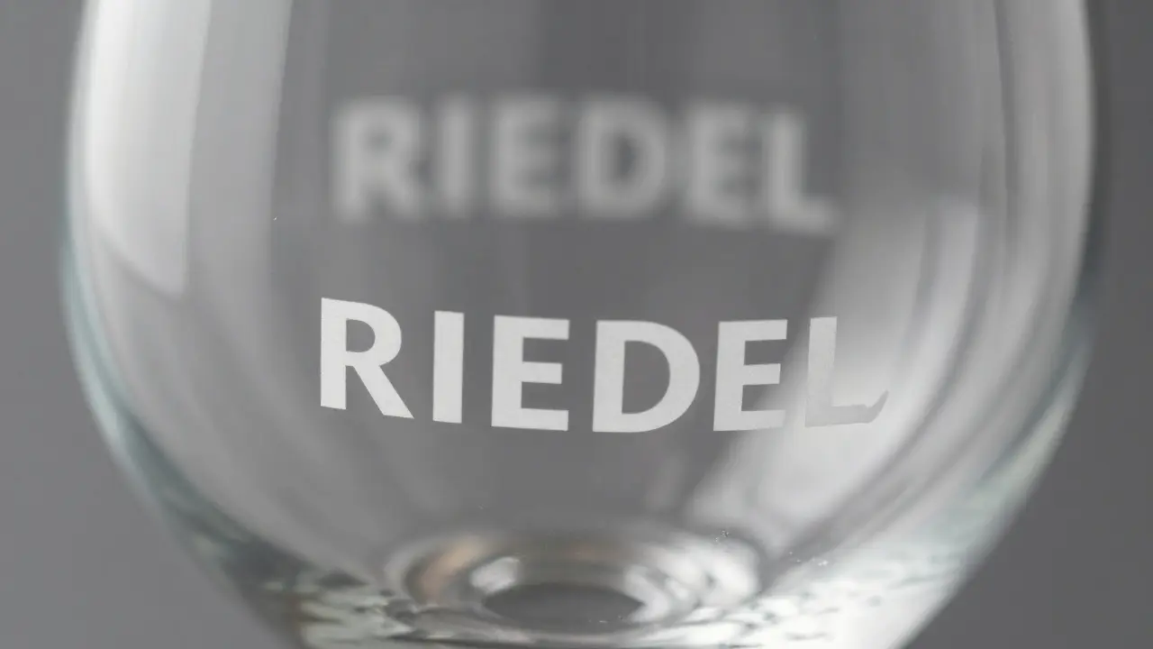 Base de una copa Riedel con grabado láser preciso de la marca, comparada visualmente con un logotipo impreso deficiente.